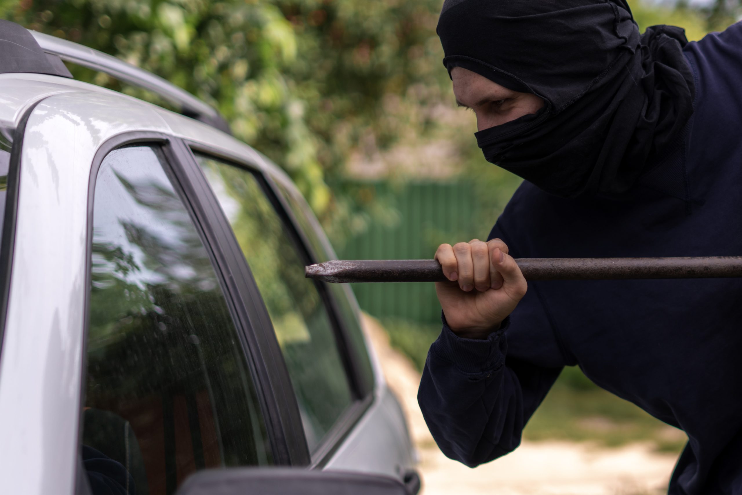 Sécuriser son domicile contre le cambriolage : la méthode complète (2026) 4 Voleur masqué en repérage près d'un véhicule, technique d'intrusion suivie