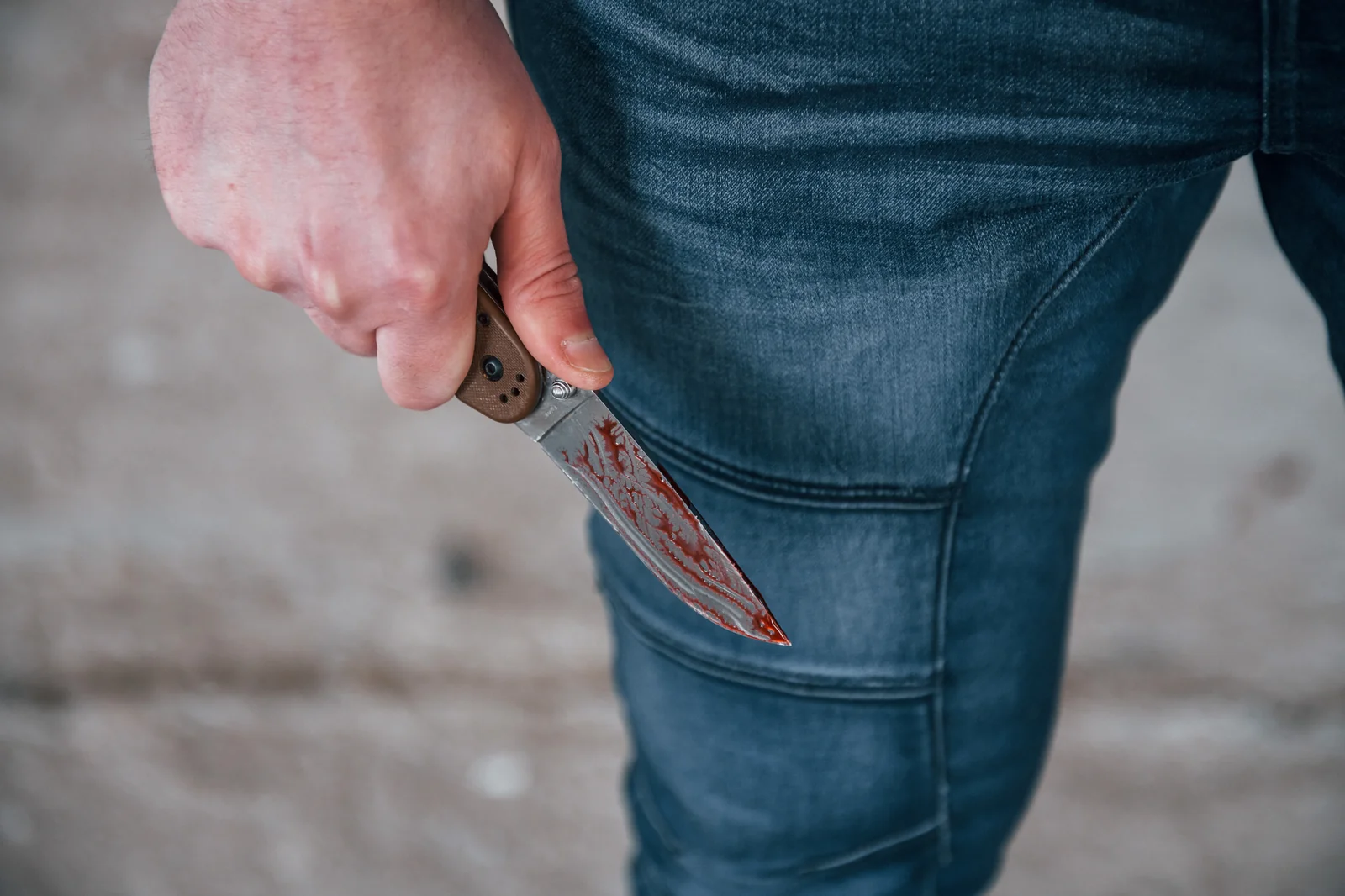 Main dissimulant un couteau le long de la jambe dans la rue, illustration des signaux pre-agression a reperer avant le passage a l acte
